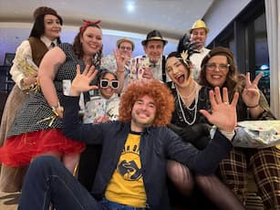 Smiling costumed group, festive, colorful atmosphere, cheerful gestures, modern backdrop.